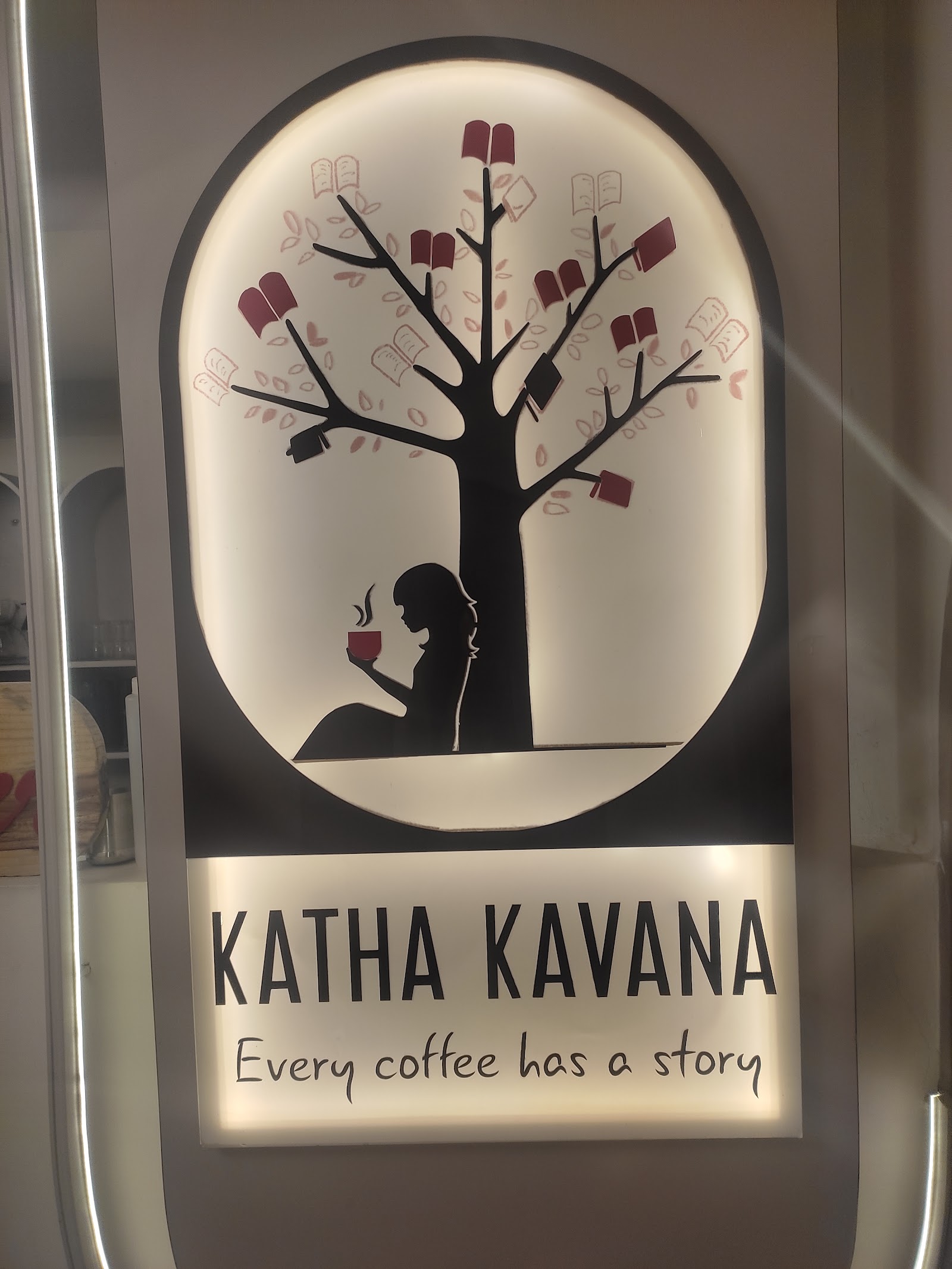 The painted house sign lit from behind at close range — the book tree, the seated reader, and the line every coffee has a story.