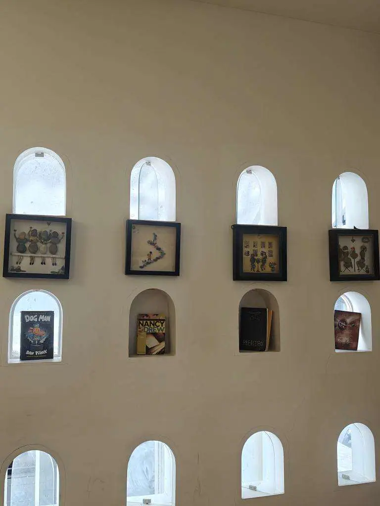 A wall of arched niches, each one holding a small framed book cover.